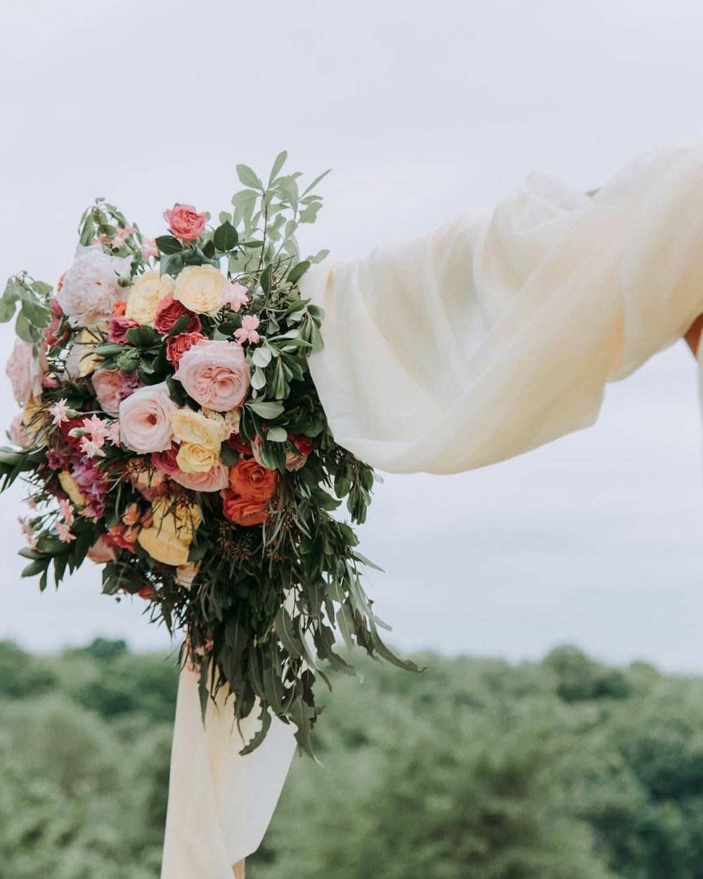 A bouquet tied to a draped wedding arch